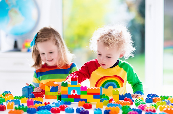 Child playing with colorful toys. Little girl and funny curly baby boy with educational toy blocks. Children play at day care or preschool. Mess in kids room. Toddlers build a tower in kindergarten.